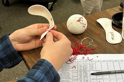A student's hands taking apart a baseball for testing in the UMass Lowell Baseball Research Center, the primary testing lab for Major League Baseball