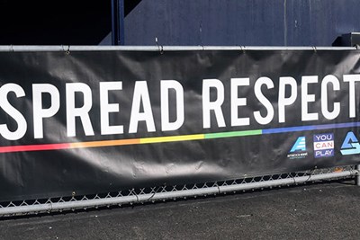 Banner hanging on fence that says Spread Respect