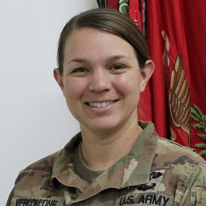 Jenna Vercollone, UML radSci student, headshot picture wearing fatigues with military flag in the background