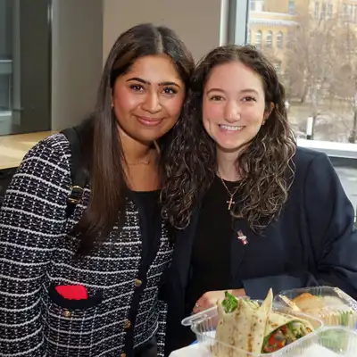 Two students smile at a table with food.