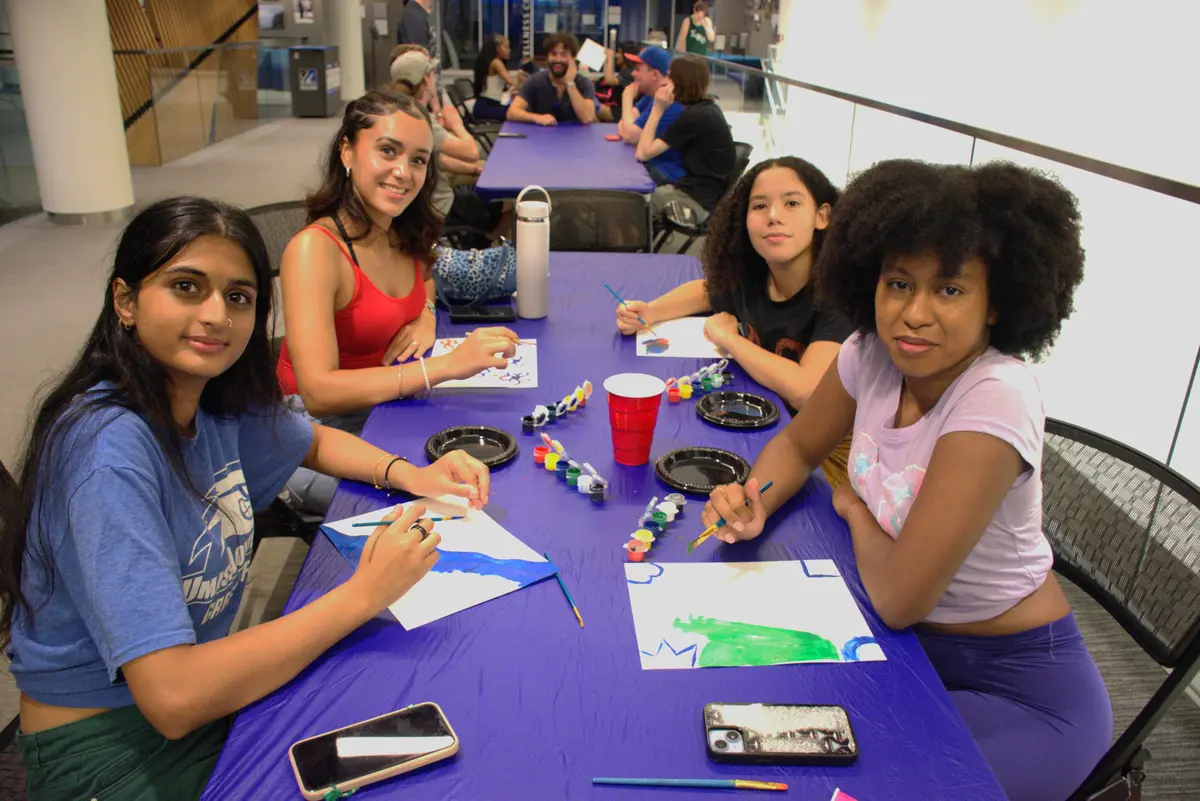 Four students doing arts and crafts at an event.