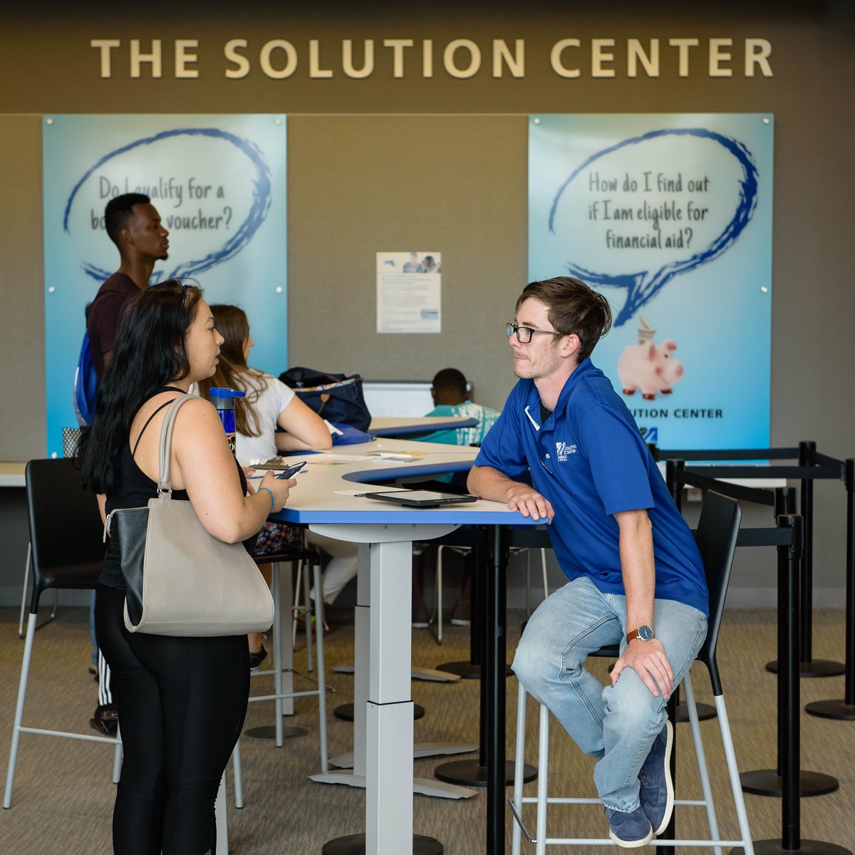 Solution Center worker counsels female student at high-top table