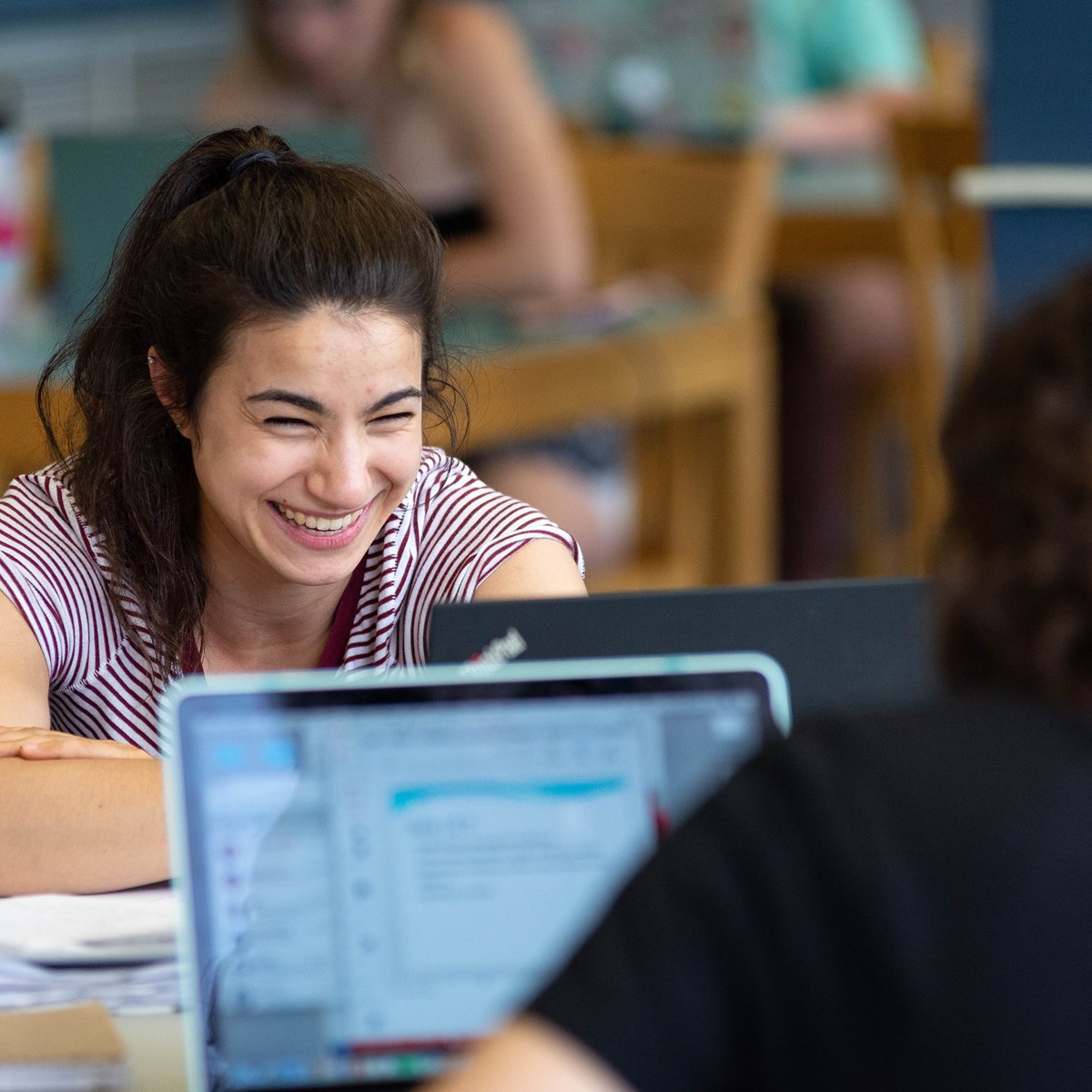 Female student smiles over top of laptop