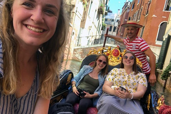 Students ride on a gondola on a canal in Venice