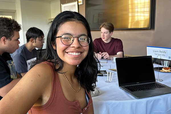 Honors psychology major Luisa Londono, who joined the new Transfer Alliance Program, smiles while sitting at a table with her peer ally, Liam Reidy