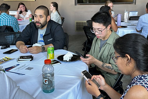 Peer ally Sergio Rodriguez, left, recommending that new transfer students download an app that will let them see their schedules, advisers and other useful information