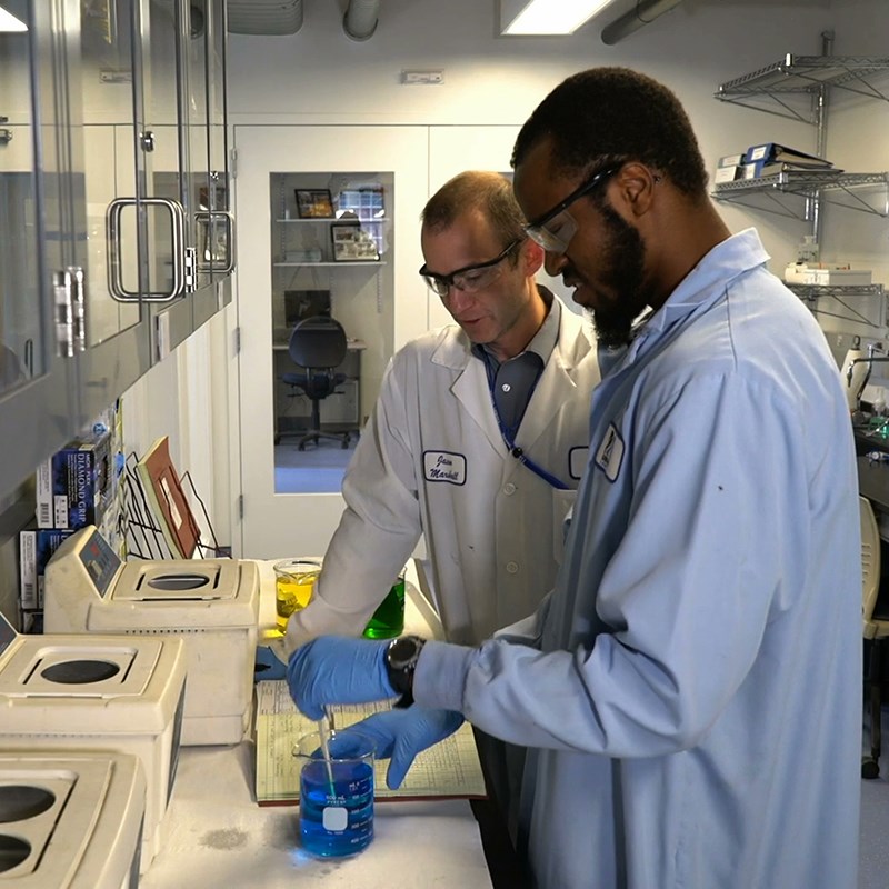 TURI staff member works with student in laboratory