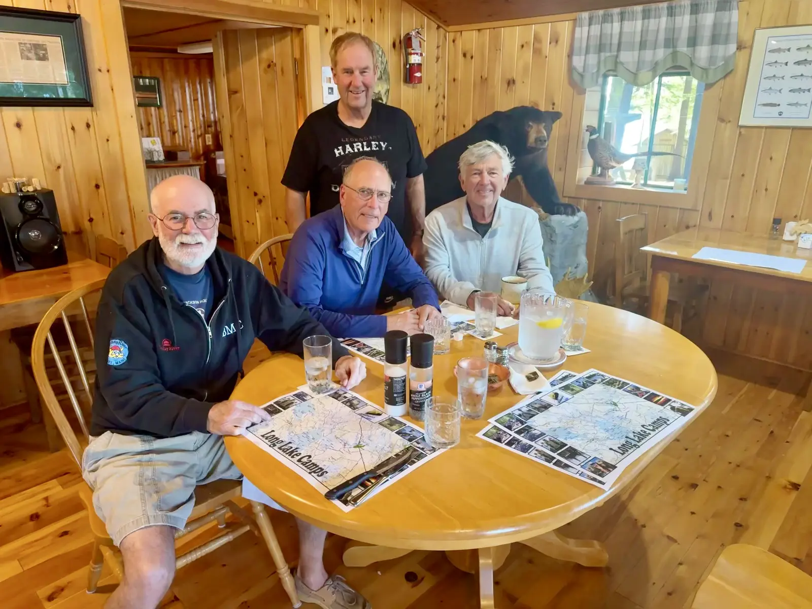 Four older men in a Maine cabin with a stuffed bear in the background