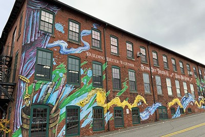 A mural on the side of a former mill building in Lawrence, Mass., that houses the Essex Art Center and a theater group