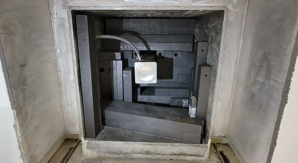 Cut out section through cement wall toward the reactor core, filled with lead around a evacuated chamber.