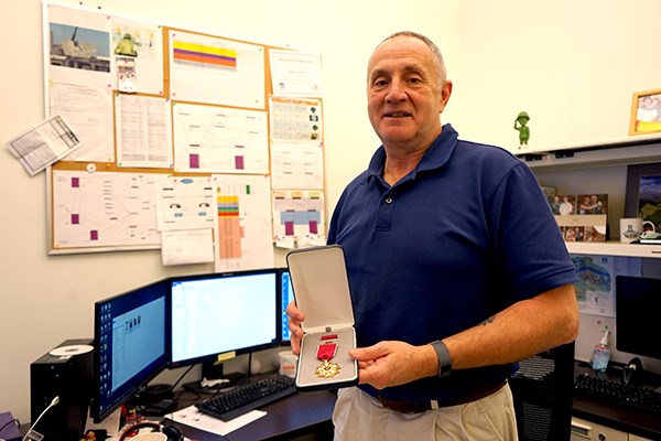 Tim Corcoran holds his Legion of Merit award in his IT office
