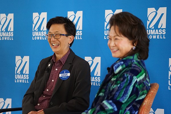 Two women with dark hair smile while taking part in a panel discussion