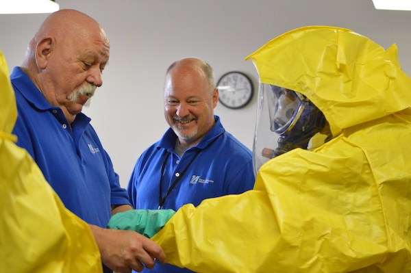 TNEC trainers help someone with their hazmat suit