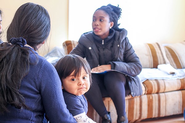 Ph.D. student Kelechi Adejumo explains the dangers of secondhand smoke to a family in the Healthy Homes project