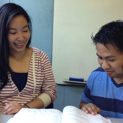 Young woman and young man share a textbook