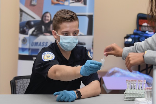 A student EMT takes a testing swab from a student