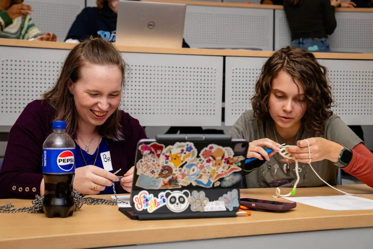 Two students sitting and crocheting.