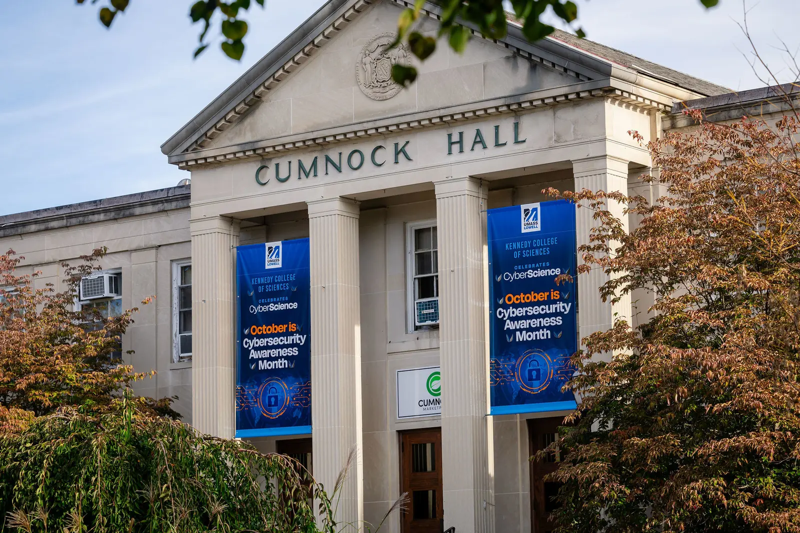 Exterior of Cumnock Hall at UMass Lowell with cybersecurity banners hung from the facade