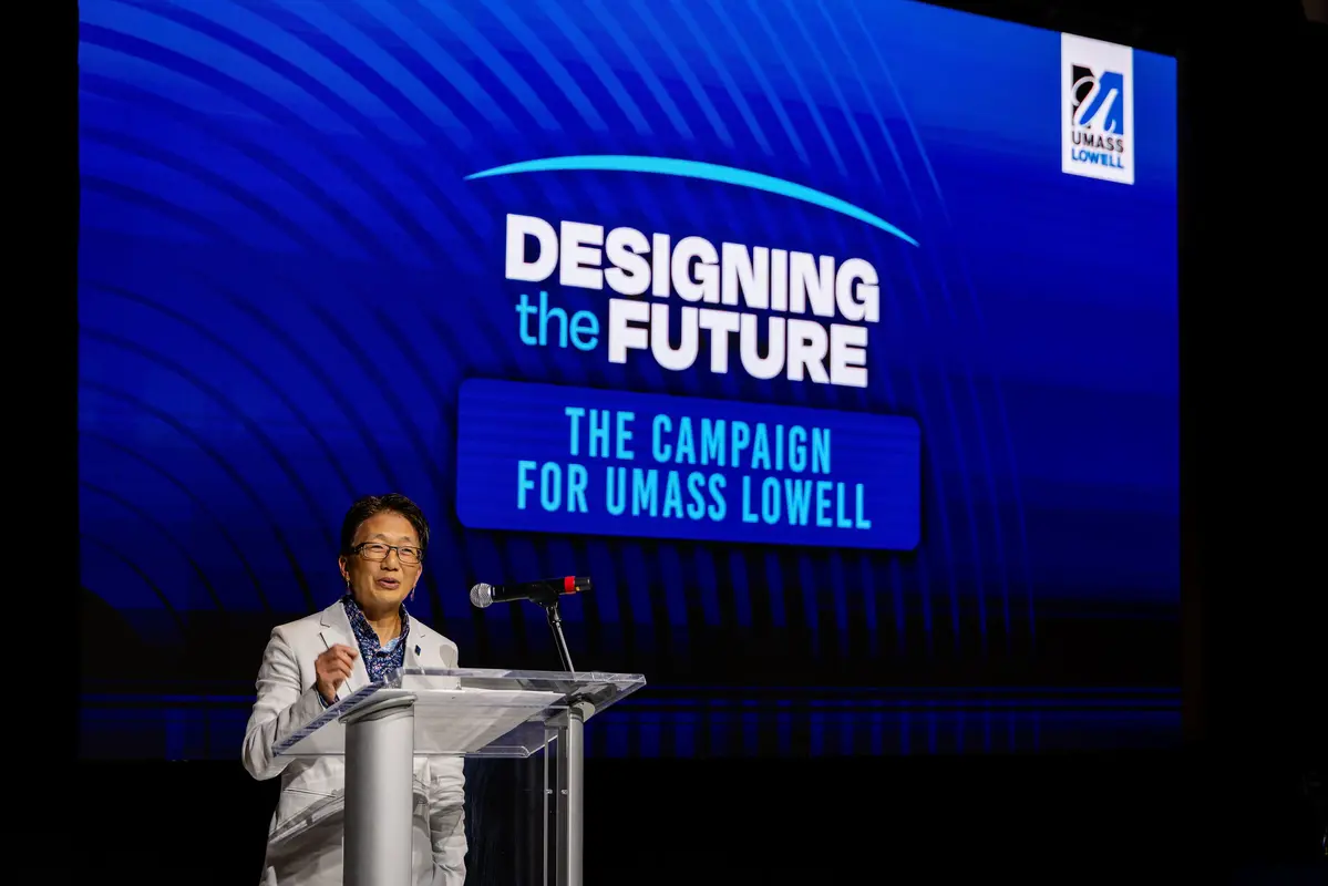 Chancellor Julie Chen at podium in front of Designing the Future The Campaign for UMass Lowell logo