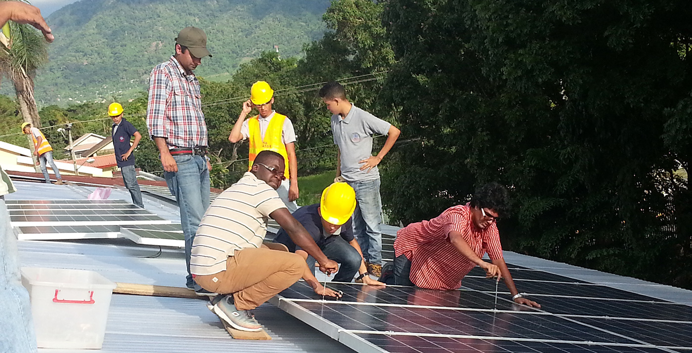 UMass Lowell students and Loyola Electrical Students installing PV modules on a roof in a developing country.