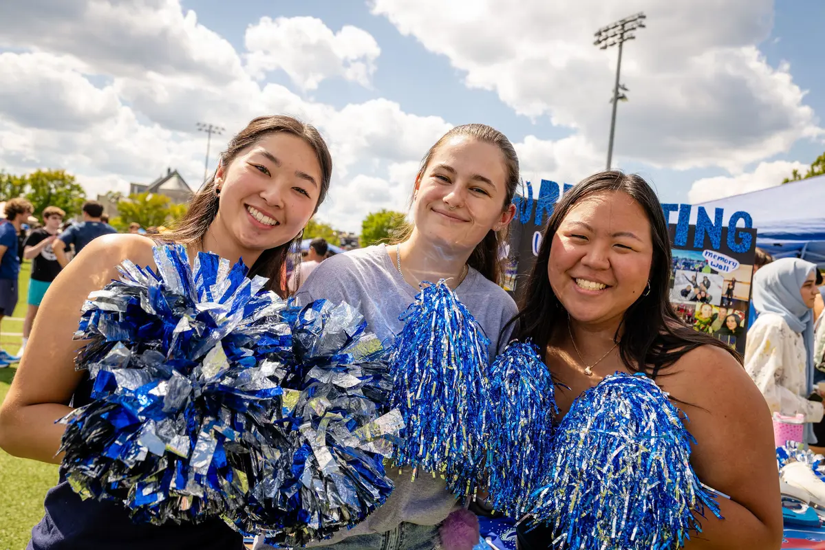 Three students with blue and white pompoms