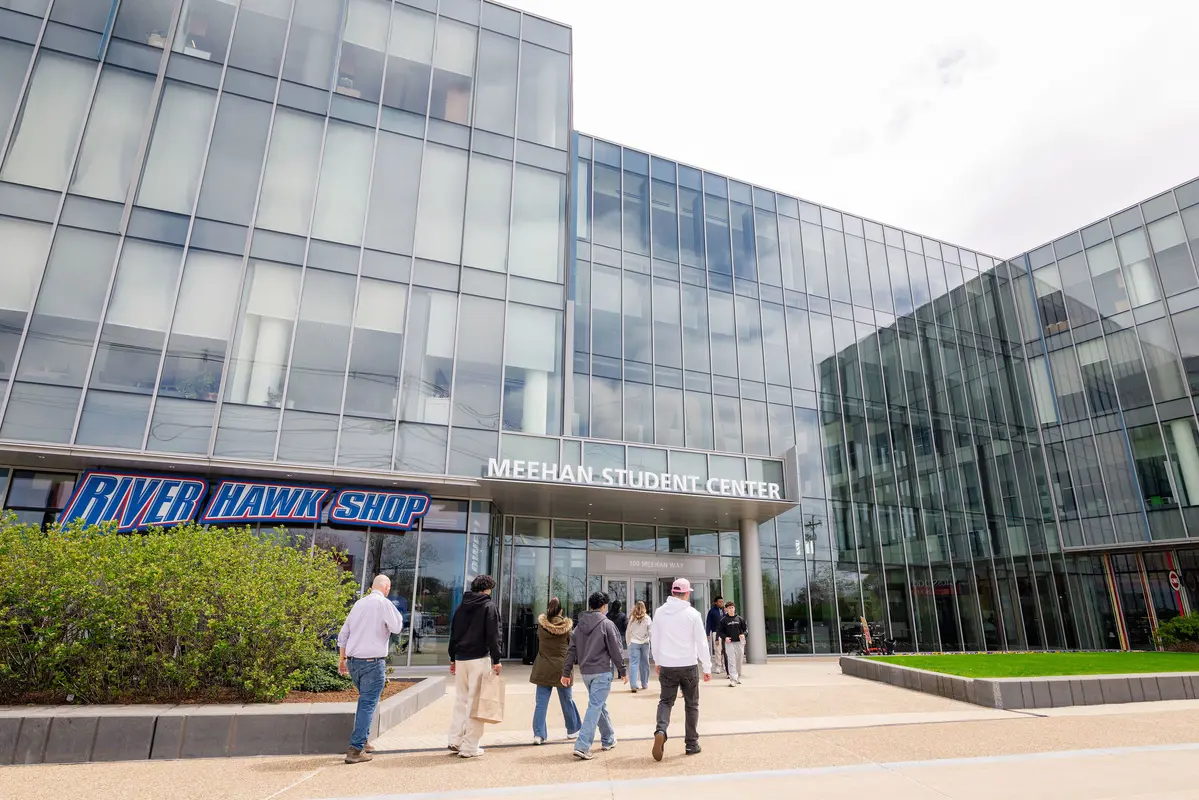 Students walk into the front of the Meehan Student Center at UMass Lowell, where the River Hawk Shop is located