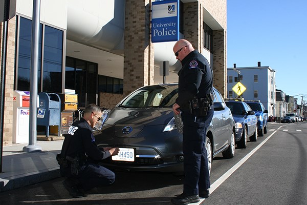 UML police officers affix a license plate to their new electric vehicle