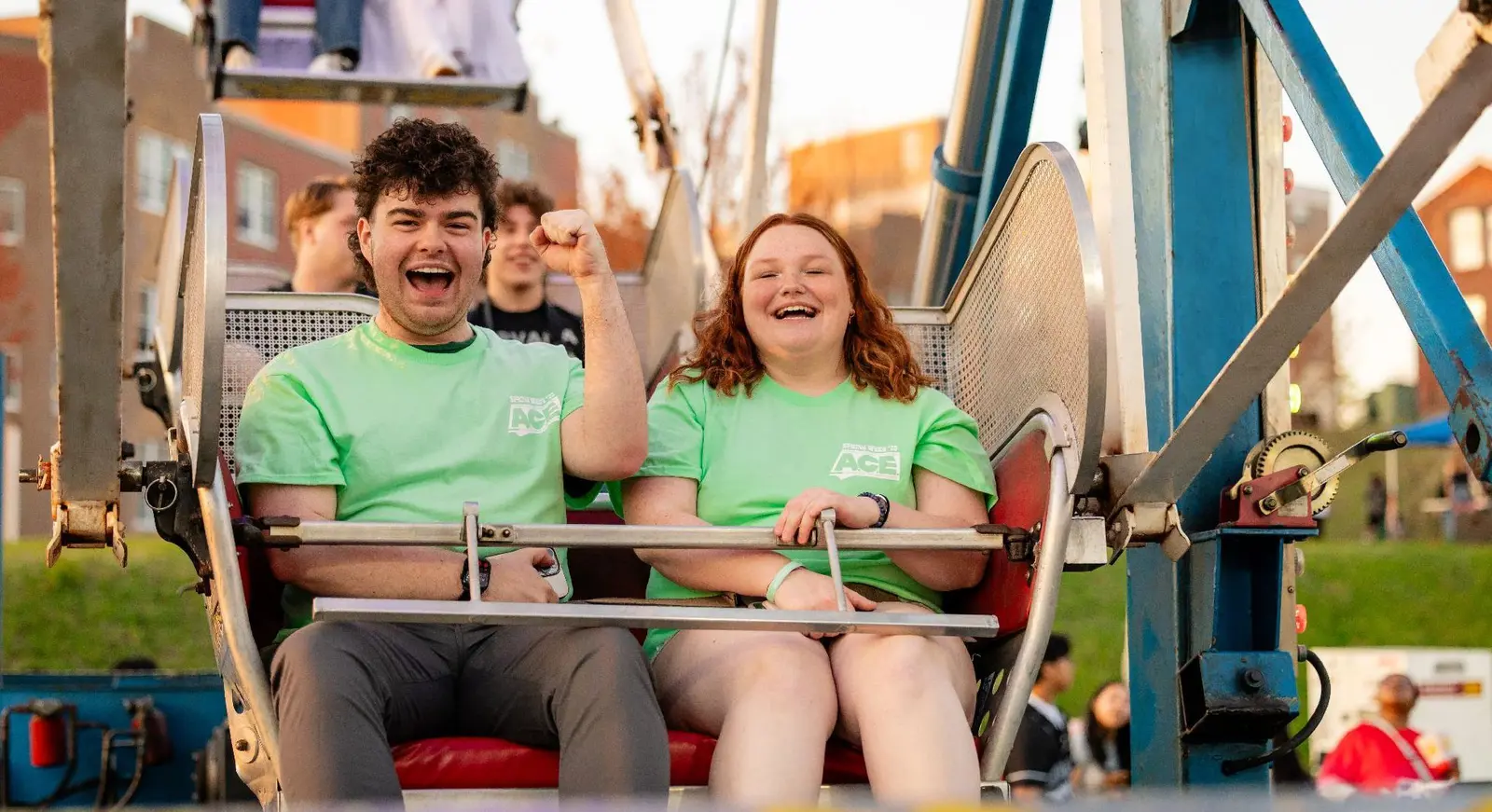 Two students cheer while riding in a Ferris wheel basket