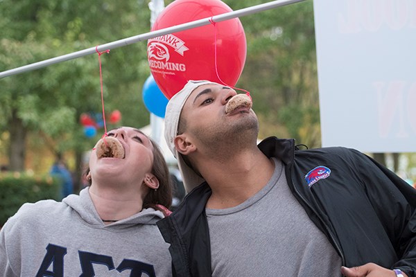 Students eat donuts hanging from strings at UML Homecoming
