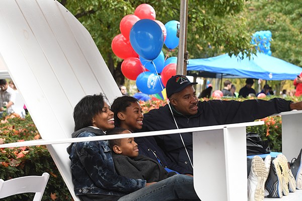 A family gets their picture taken in a giant lawn chair at UML Homecoming
