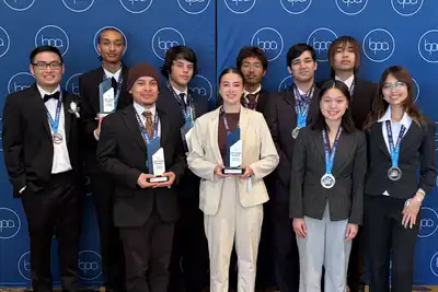 Ten young men and women in professional attire pose for a group photo while holding trophies and wearing medals.
