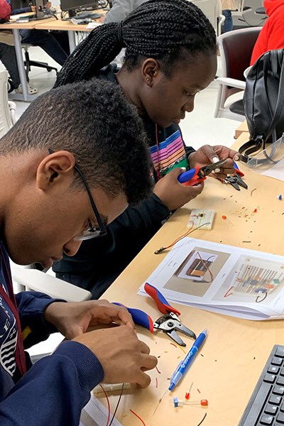Students from Lowell High School work on circuits following instructions from UTeach student Javier Palma