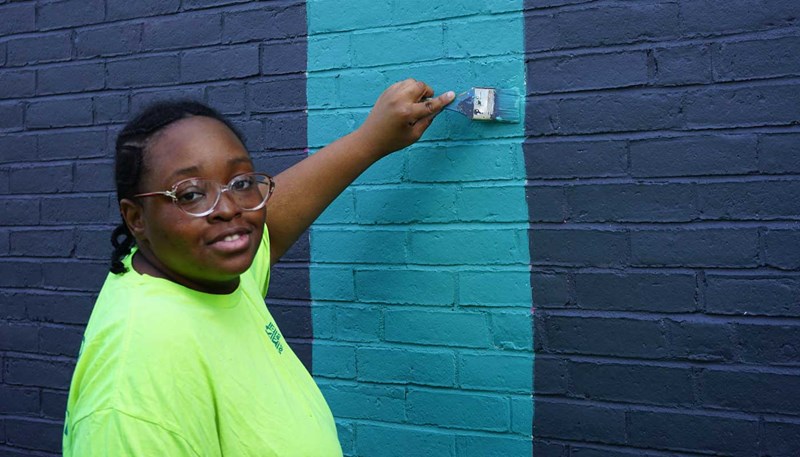 Urdilinya Smith painting the new mural on South Campus at UMass Lowell