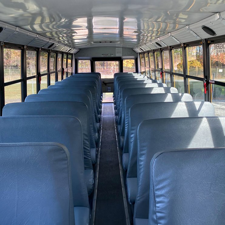 The interior of a yellow school bus. There's two rows of grey bench seats.
