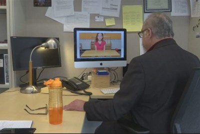 Prof. Richard Serna looks at computer screen with virtual child on it.