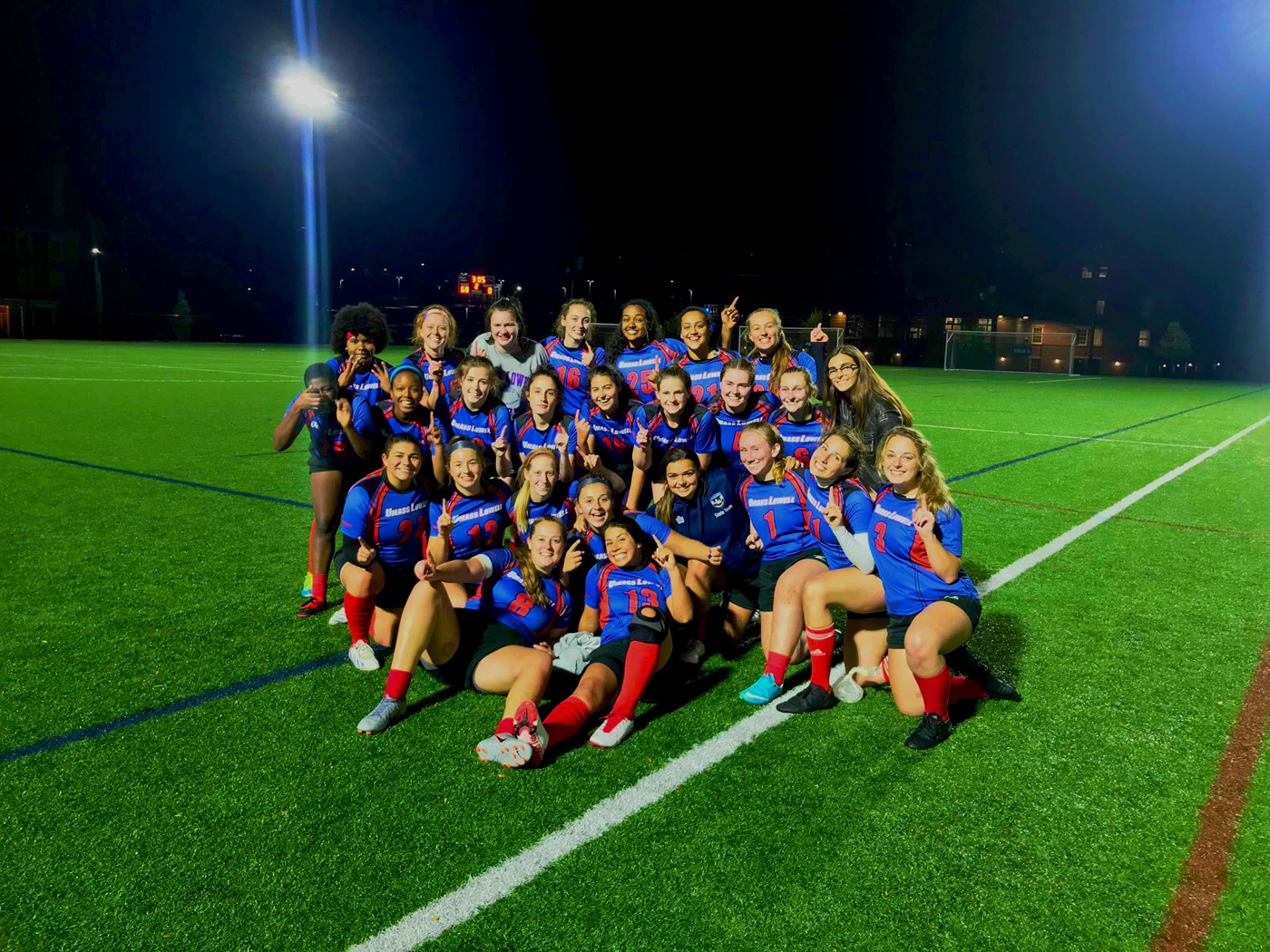 Women's rugby poses in uniform on the east campus turf complex