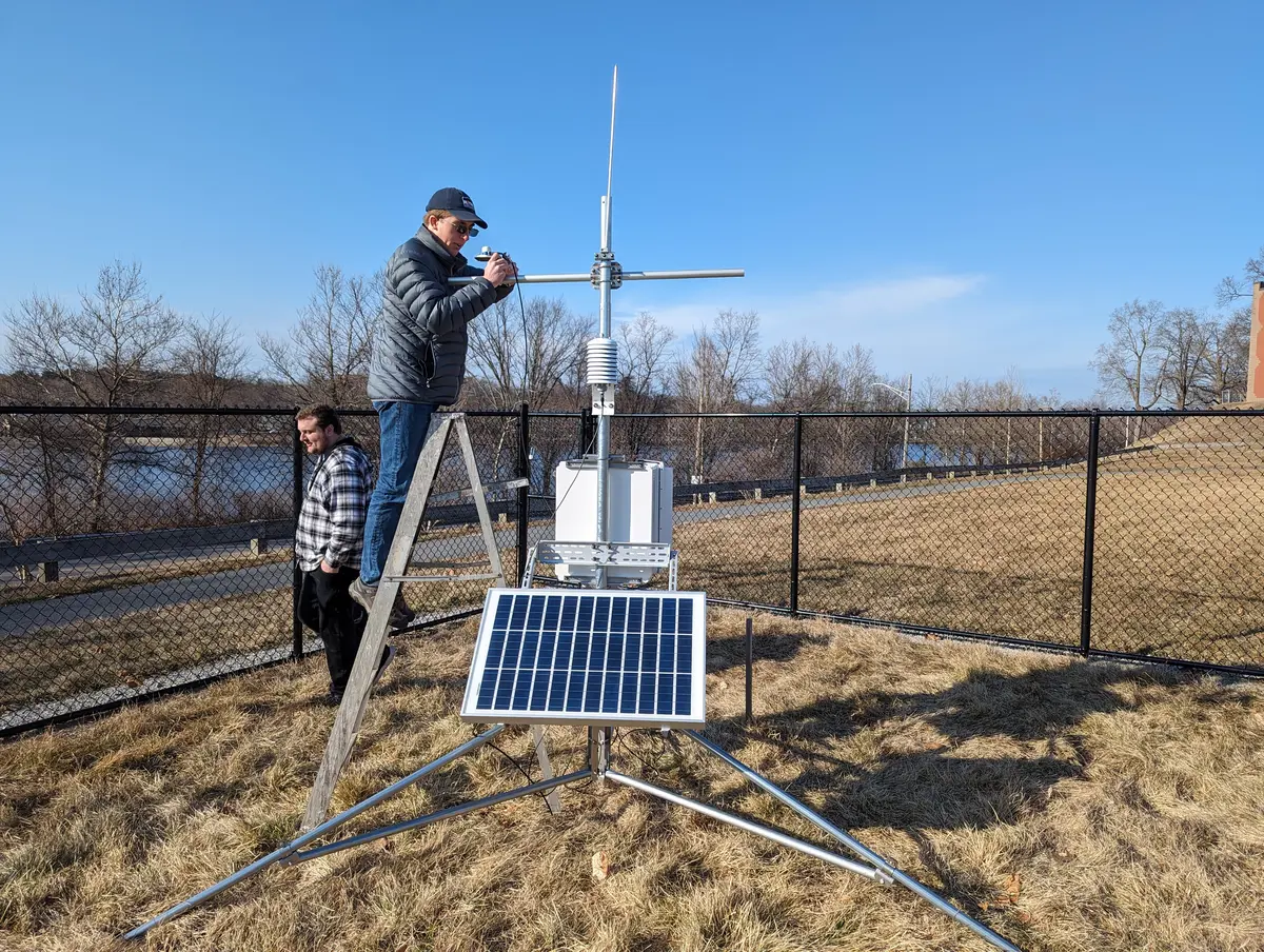 Man adjusts solar panel on site of weather station