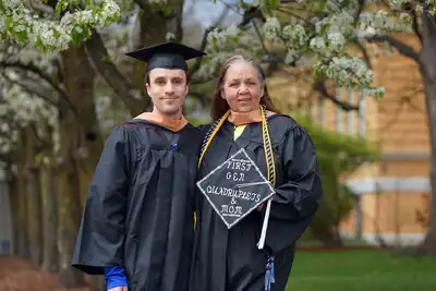 Six people pose for a photo outside at a college commencement.