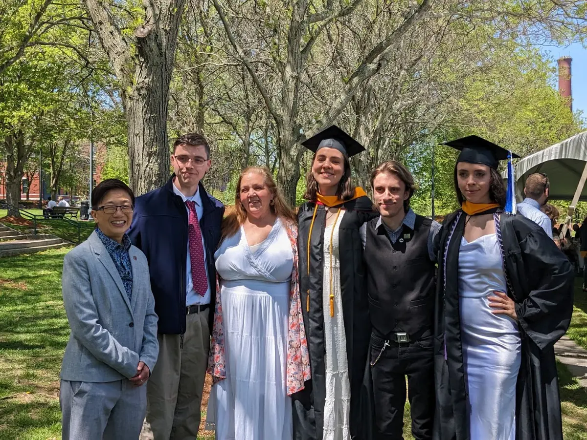 Six people pose for a photo outside at a college commencement.
