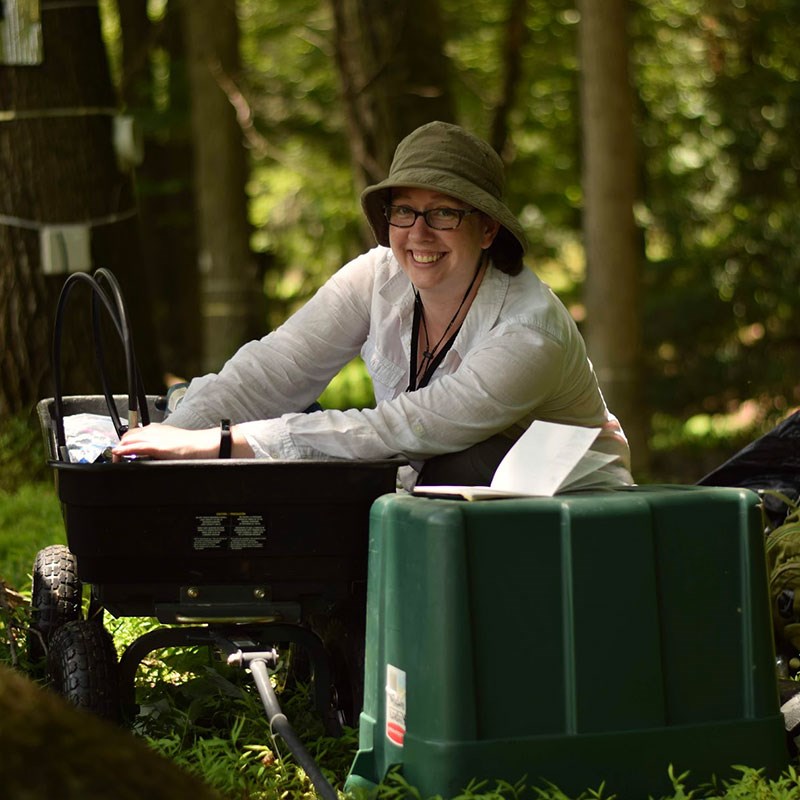 Joy Winbourne sitting and doing field work in a forest