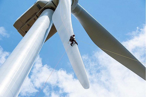 Photo of a large turbine blade with a worker next to it