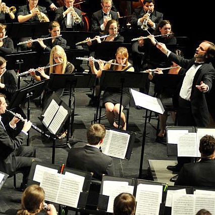 Conductor leads wind section of orchestra