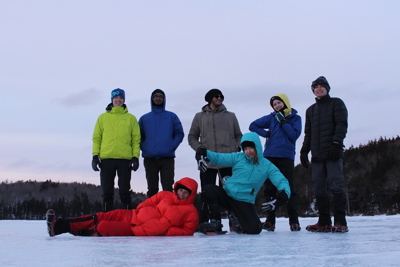 Winter hikers making silly poses on a frozen lake.
