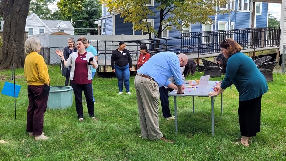 Staff members work at tables in grassy yard