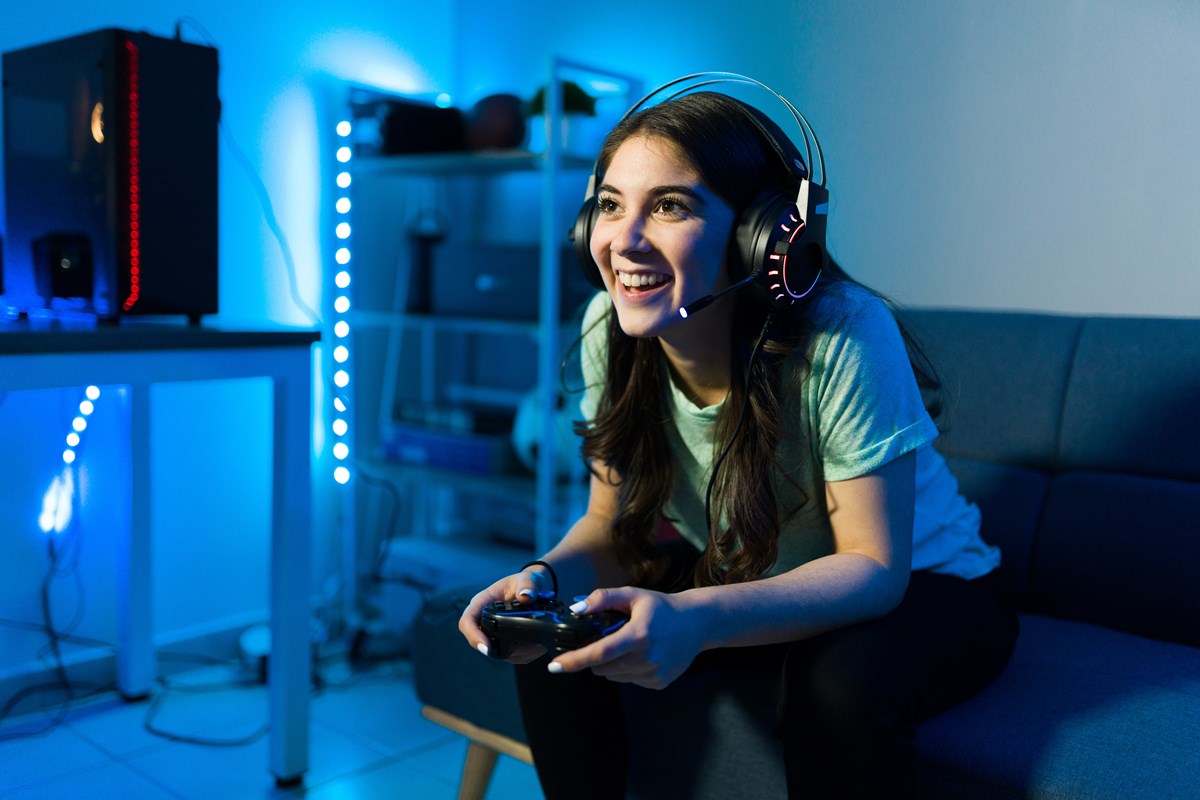 Young woman playing online game smiling while talking to another online player.