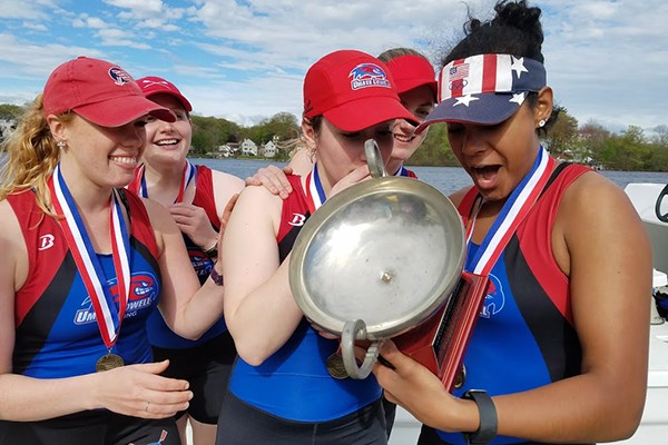 The women's varsity four rowers look at their trophy