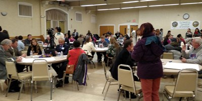 People seated at round tables talking at the Lowell Senior Center