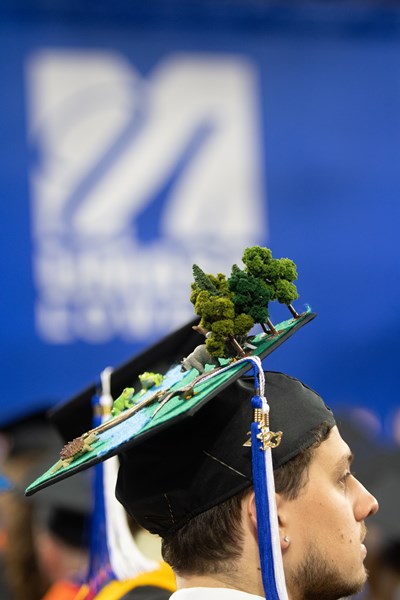 Student with trees and zoo animals on mortarboard