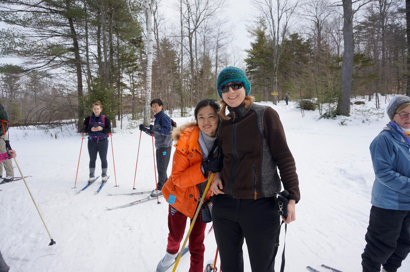 Students pose for picture smiling while cross country skiing.