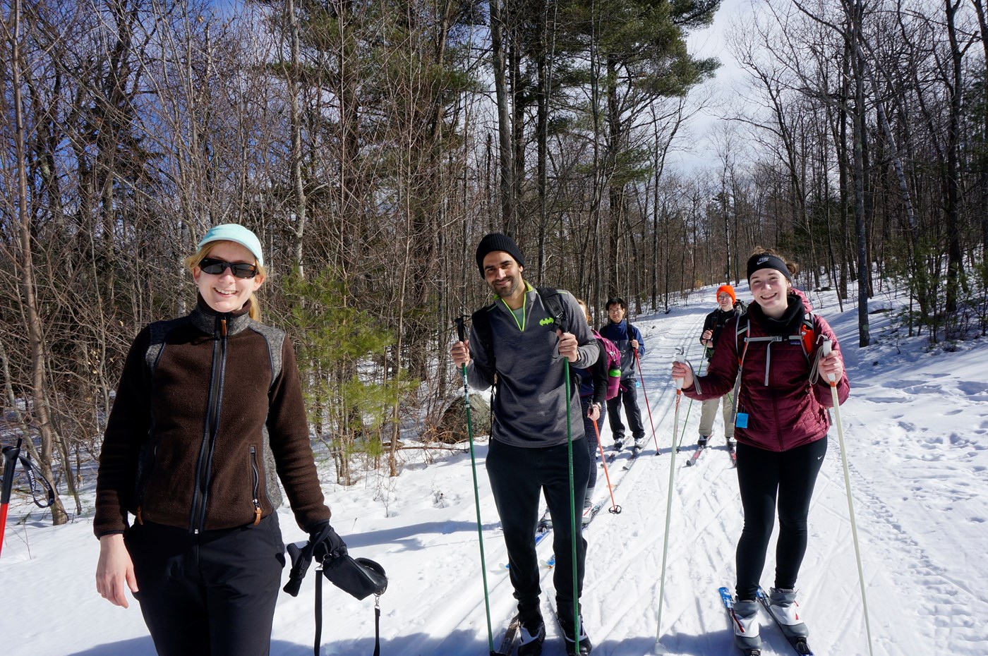 Students pose for picture smiling while cross country skiing.